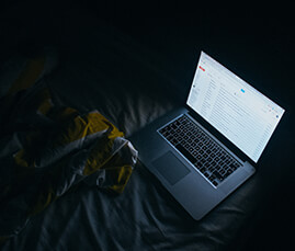 Laptop on bed showing emails